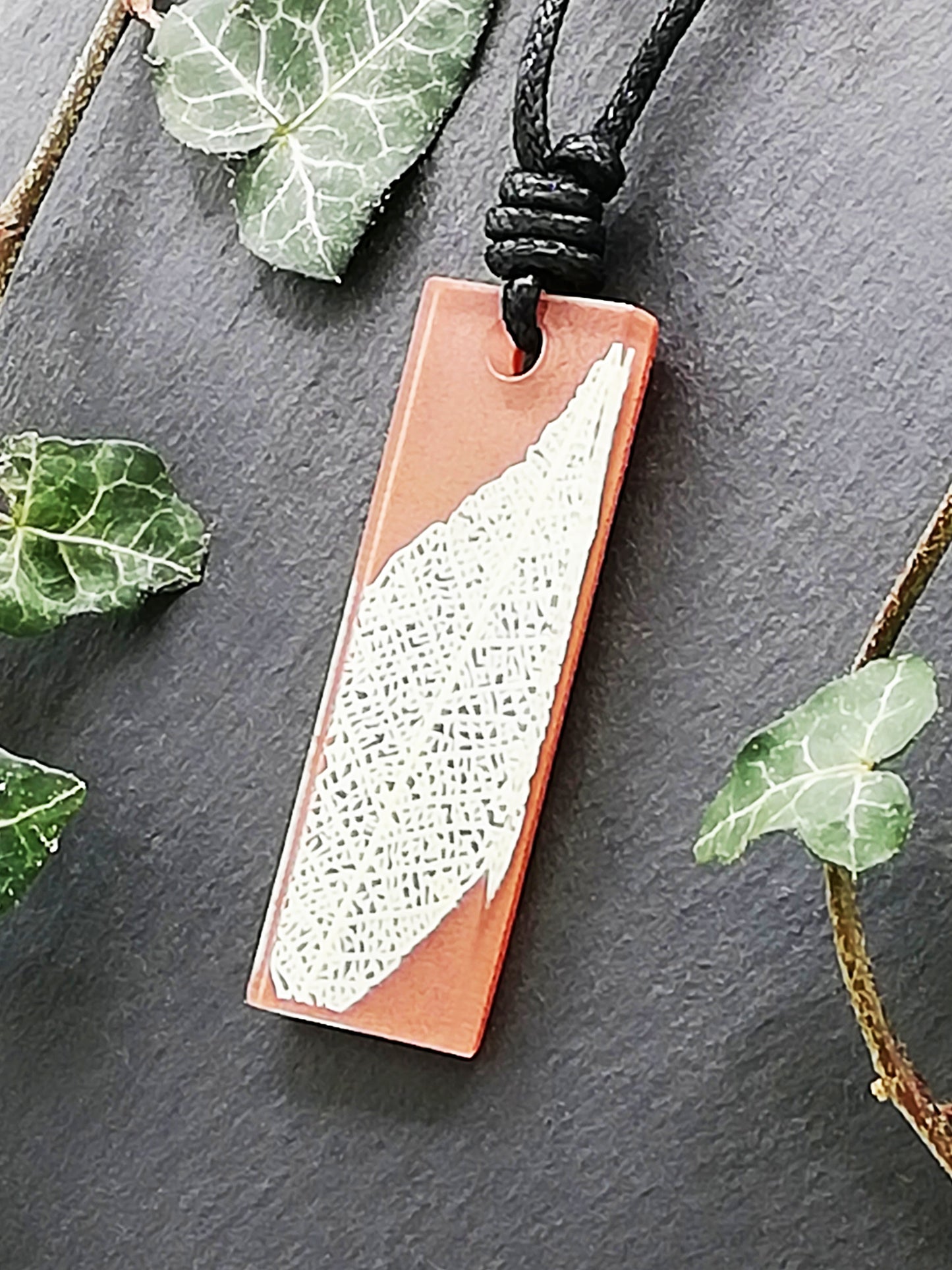 Warm brown rectangular pendant with cream leaf skeleton design, displayed at an angle to show the layers within the pendant