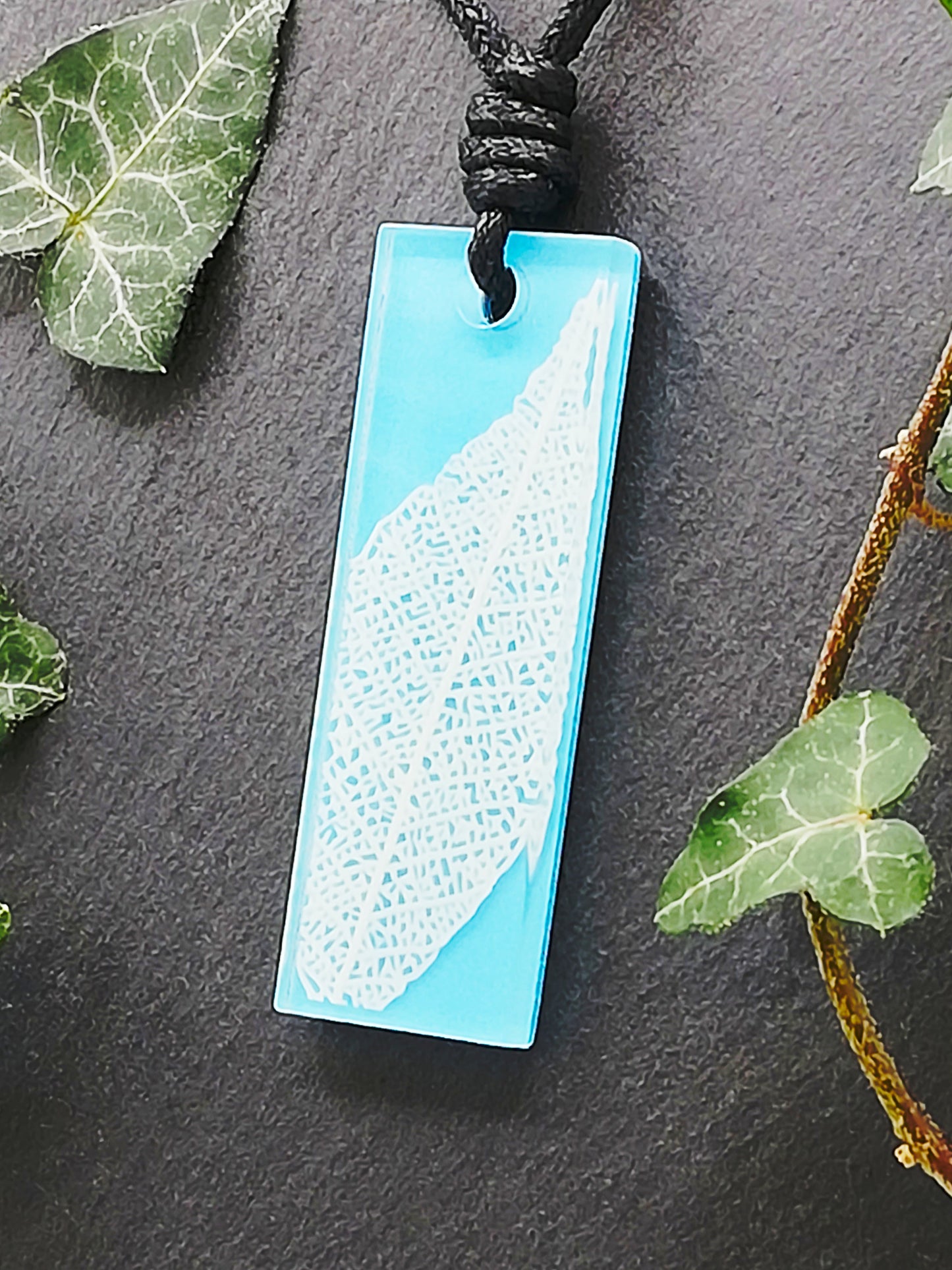 Light blue rectangular pendant with white leaf skeleton design, displayed at an angle to show the layers within the pendant