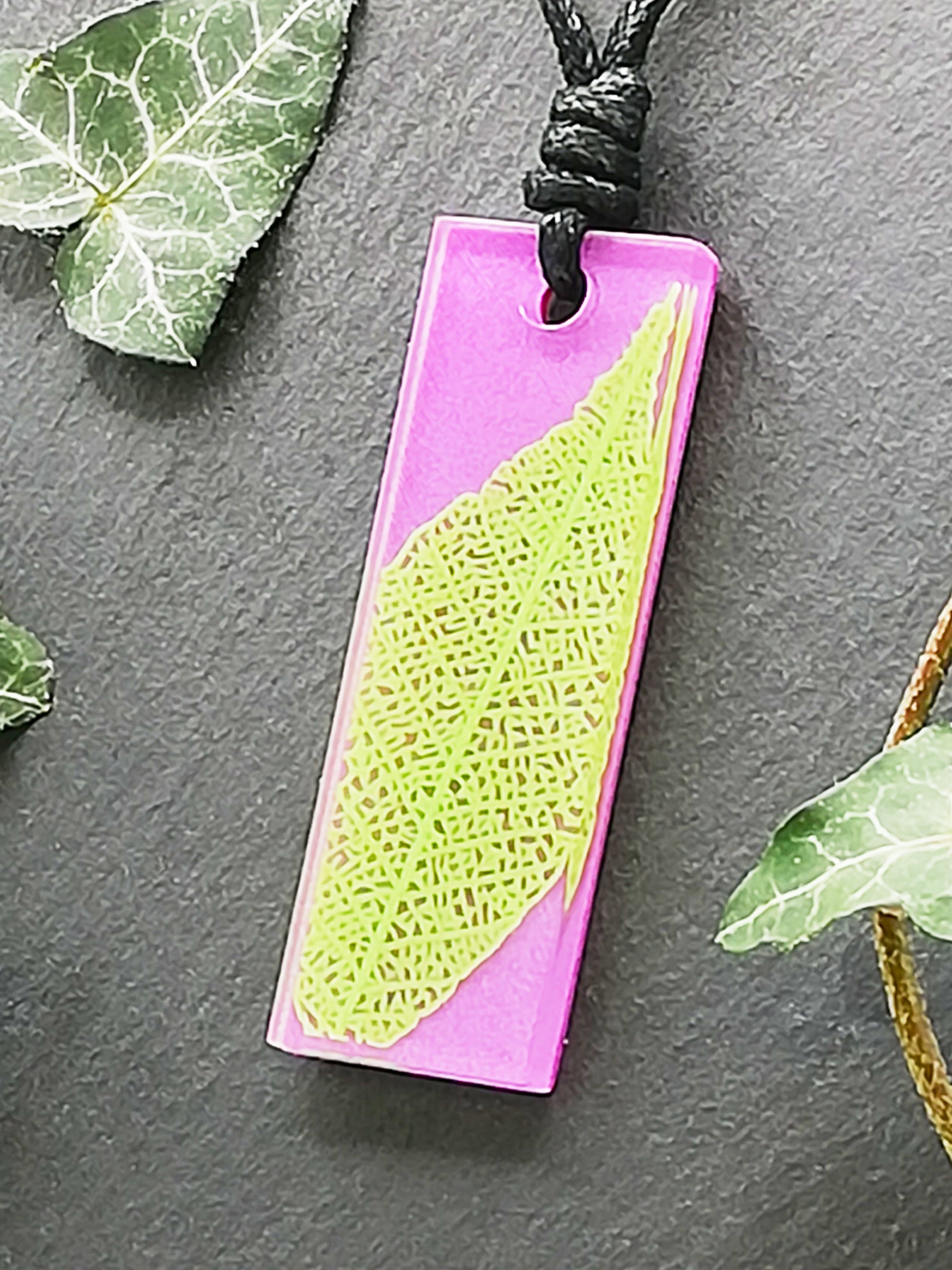 Purple rectangular pendant with bright green leaf skeleton design, displayed at an angle to show the layers within the pendant