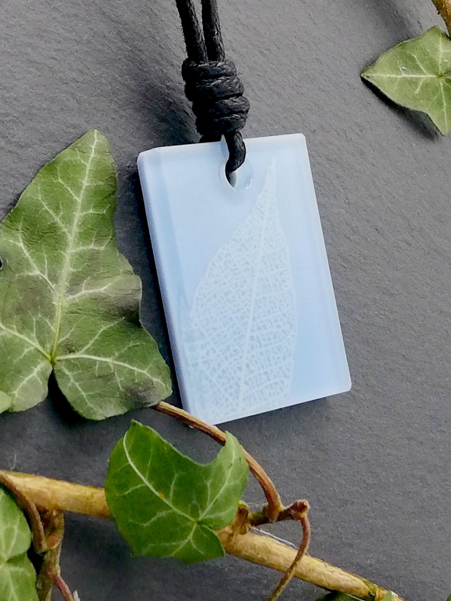 Light blue rectangular pendant with white leaf skeleton design, displayed at an angle to show the layers within the pendant