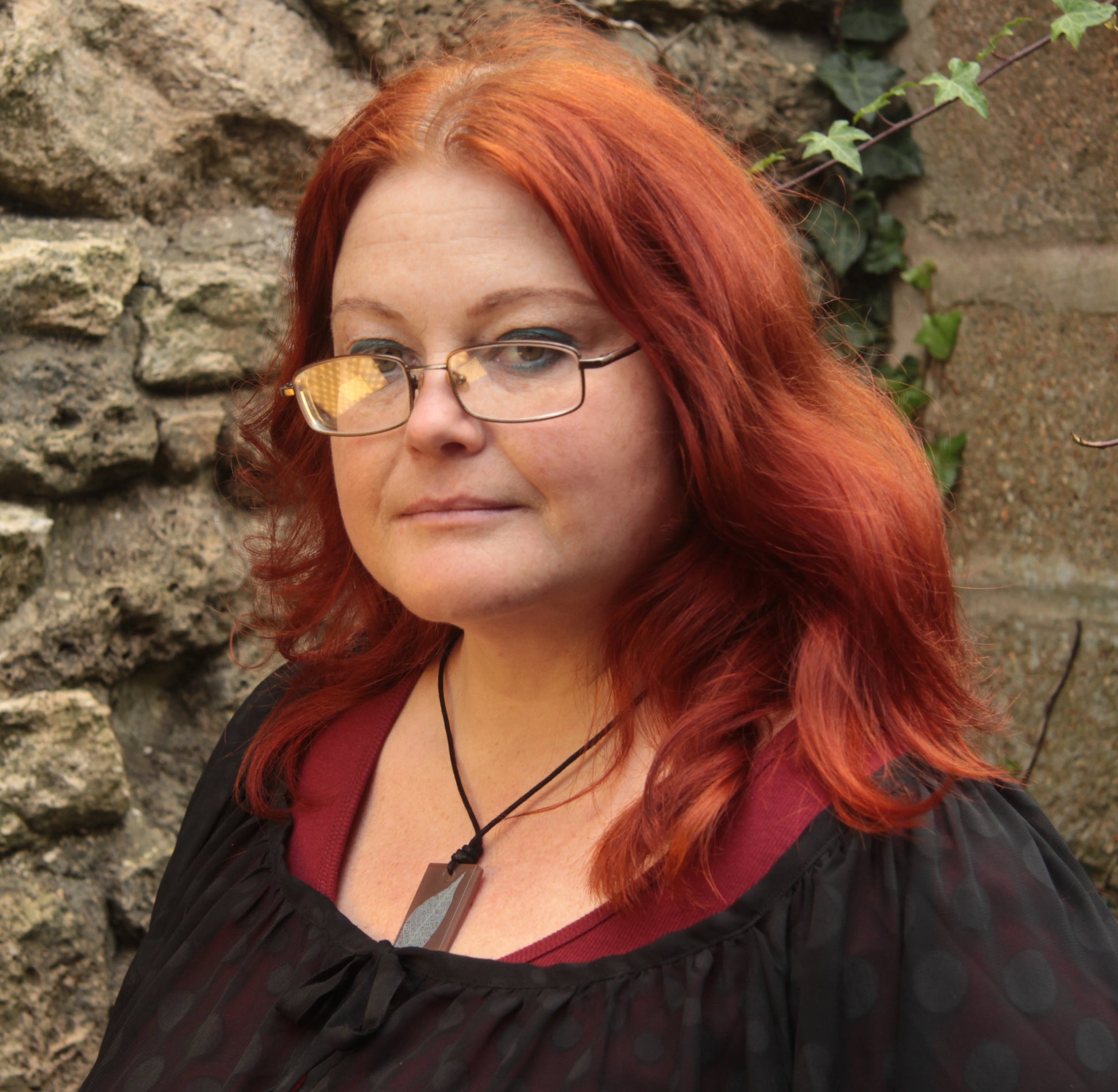 Red haired woman wearing a warm brown rectangular pendant with cream leaf skeleton design 